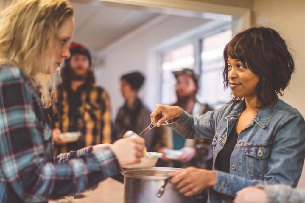 Woman serving soup in a soup kitchen